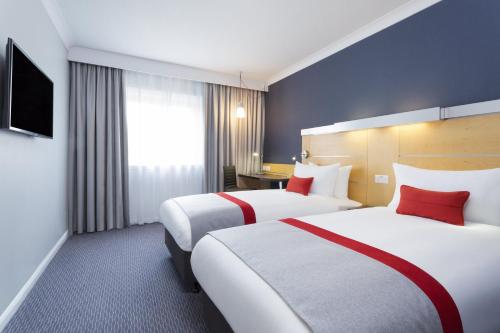 a hotel room with two beds with red pillows at Holiday Inn Express Southampton - M27, J7 by IHG in Southampton