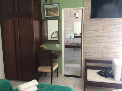 a bathroom with a sink and a mirror and a chair at Pousada Aguas de Ibira in Termas do Ibirá