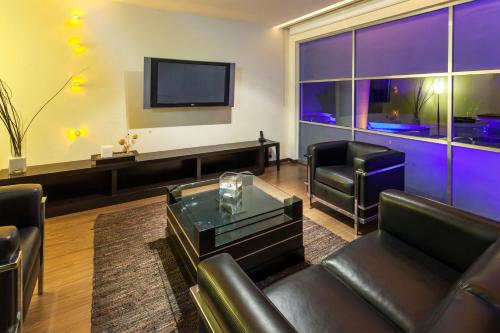 a living room with leather furniture and a flat screen tv at Crowne Plaza Toluca - Lancaster by IHG in Toluca