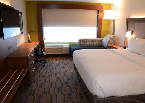 a hotel room with a bed and a flat screen tv at Holiday Inn Express & Suites - Pittsburgh - Monroeville by IHG in Monroeville