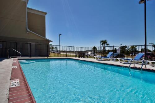 a large swimming pool with chairs and a building at Candlewood Suites Lake Charles-Sulphur, an IHG Hotel in Sulphur