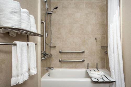 a bathroom with a tub and a shower with towels at Holiday Inn San Antonio Northwest- SeaWorld Area, an IHG Hotel in San Antonio