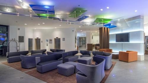 a waiting room with blue chairs and a flat screen tv at Holiday Inn Express Puebla by IHG in Puebla