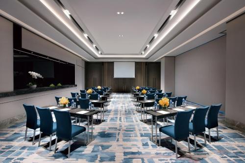 une salle avec des tables, des chaises et un écran de projection dans l'établissement Crowne Plaza Shanghai Pujiang, an IHG Hotel, à Shanghai