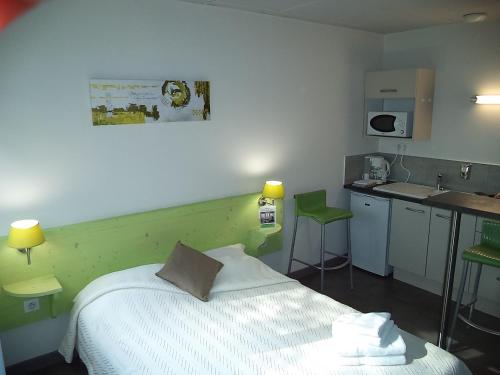 ein kleines Schlafzimmer mit einem Bett und einem Waschbecken in der Unterkunft West Appart' Hôtel in Bessines