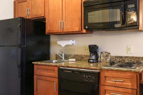 a kitchen with a black refrigerator and a sink at Candlewood Suites Slidell Northshore by IHG in Slidell
