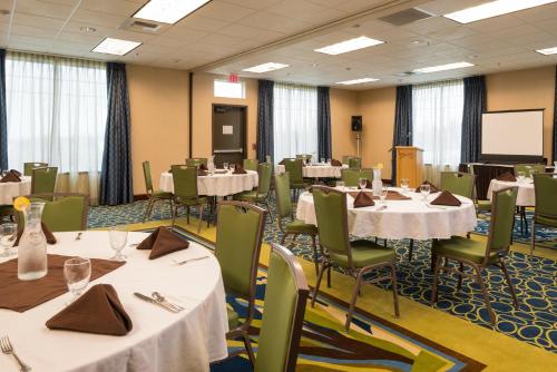 a conference room with tables and chairs and a screen at Holiday Inn Express Hotel & Suites North Sequim by IHG in Sequim