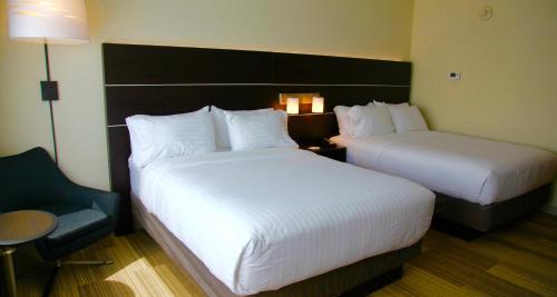 a hotel room with two beds and a chair at Holiday Inn Express & Suites Oswego by IHG in Oswego