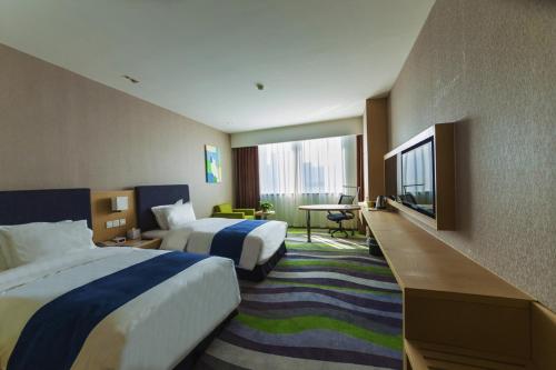 a hotel room with two beds and a flat screen tv at Holiday Inn Express Jinan High-Tech Zone by IHG in Jinan