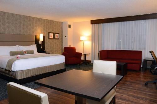 a hotel room with a bed and a table and chair at The Armon Stamford Hotel & Conference Center in Stamford