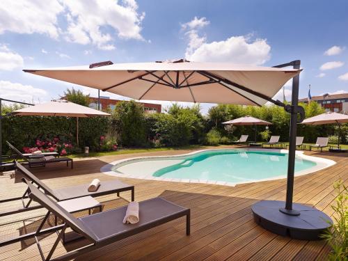 a patio with an umbrella and a swimming pool at Holiday Inn Express Toulouse Airport by IHG in Blagnac