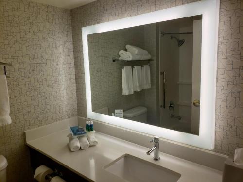 La salle de bains est pourvue d'un lavabo et d'un grand miroir. dans l'établissement Holiday Inn Express Portland West/Hillsboro, an IHG Hotel, à Hillsboro