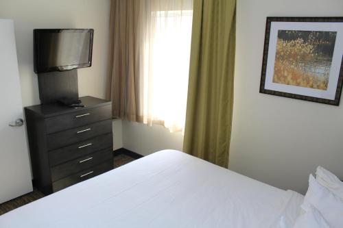 a bedroom with a bed and a dresser with a television at Candlewood Suites - East Syracuse - Carrier Circle by IHG in East Syracuse