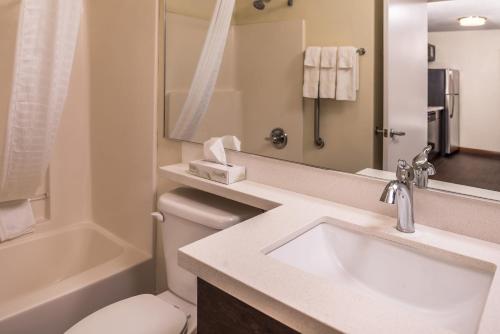 a bathroom with a sink and a toilet and a mirror at Candlewood Suites Kansas City, an IHG Hotel in Kansas City