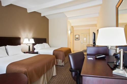 a hotel room with two beds and a desk at Holiday Inn Express- North Palm Beach and IHG Hotel in Juno Beach