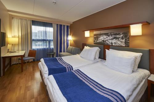 a hotel room with a large bed and a desk at Holiday Inn Tampere - Central Station by IHG in Tampere