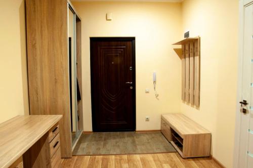 pasillo con puerta marrón y banco de madera en Wonderful flat on city center (Mukachivska 4/16) en Úzhgorod