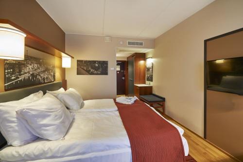 a hotel room with a large white bed with a red blanket at Holiday Inn Tampere - Central Station by IHG in Tampere