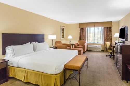 a hotel room with a large bed and a living room at Holiday Inn Express Hotel & Suites Nogales by IHG in Nogales