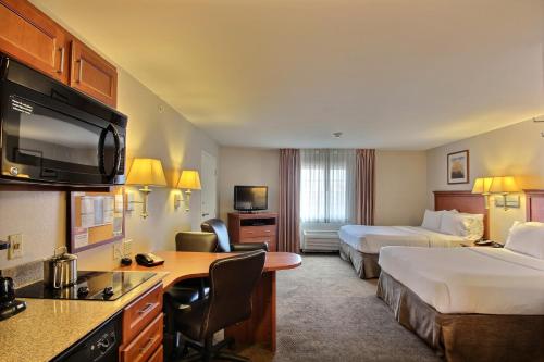 a hotel room with two beds and a desk at Candlewood Suites Milwaukee Airport - Oak Creek, an IHG Hotel in Greendale