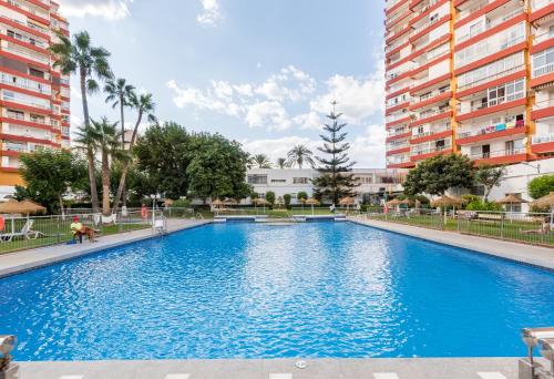 a large blue swimming pool with buildings in the background at Apartamento Diana ii in Benalmádena