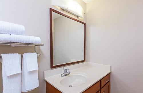 a bathroom with a sink with a mirror and towels at Candlewood Suites Owasso, an IHG Hotel in Owasso