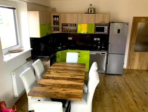 cocina con mesa de madera y sillas blancas en Luxury Keilberg Apartment, en Loucná pod Klínovcem
