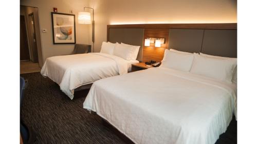 two beds in a hotel room with white sheets at Holiday Inn Express Hotel & Suites Norfolk by IHG in Norfolk