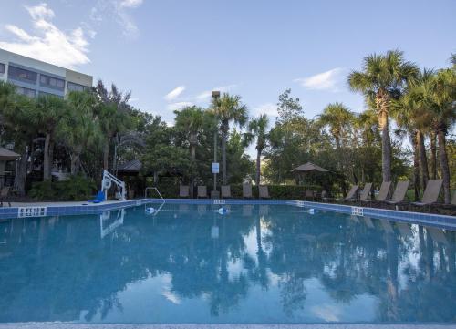 a large swimming pool with chairs and palm trees at Holiday Inn Orlando International Airport by IHG in Orlando