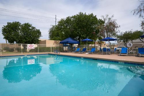 a swimming pool with blue chairs and umbrellas at Holiday Inn Express Scottsdale North by IHG in Scottsdale