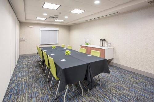 a conference room with a black table and yellow chairs at Holiday Inn Express Kansas City - at the Legends! by IHG in Kansas City
