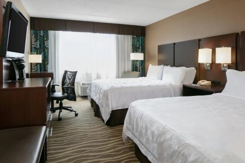 a hotel room with two beds and a desk at Holiday Inn Hotel & Suites Overland Park-West by IHG in Overland Park