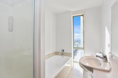a white bathroom with a tub and a sink and a bath tub at Apartment in the heart of the city in Christchurch