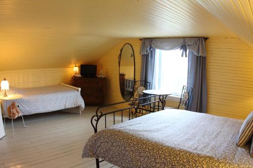 a bedroom with two beds and a mirror and a window at La Grange aux Hiboux Gîte et Restaurant B&B in La Baie