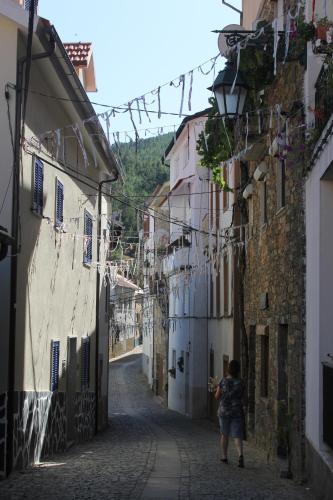 a woman walking down a street in an alley at Casa do Sapateiro in Sobral de São Miguel
