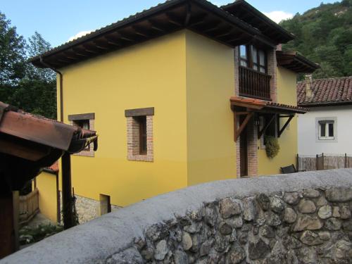 una casa amarilla detrás de una pared de piedra en CASA RURAL LA MONTESINA, en Cangas de Onís