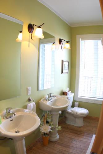 a bathroom with two sinks and a toilet and a mirror at La Grange aux Hiboux Gîte et Restaurant B&B in La Baie
