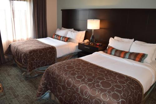 a hotel room with two beds and a lamp at Staybridge Suites Myrtle Beach-Fantasy Harbour by IHG in Myrtle Beach