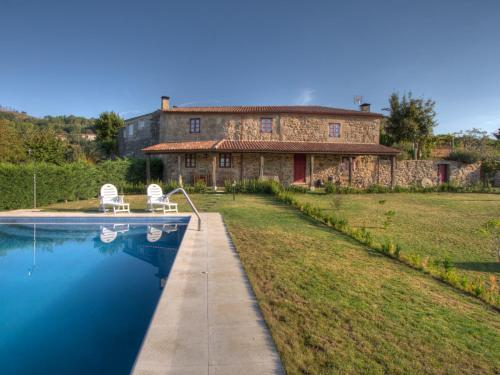 uma grande casa de pedra com uma piscina em frente em Casa Baralló em Lobios