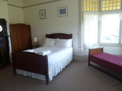 a bedroom with a bed with white sheets and a window at Claremont Farmhouse in Derby