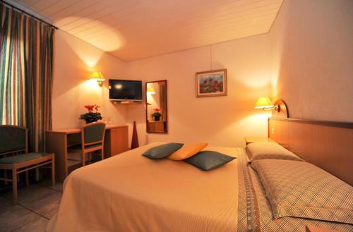 a hotel room with a bed with two pillows on it at Hotel Ristorante Grotto Serta in Lamone