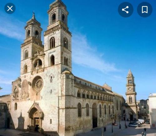 a large stone building with a clock tower on it at La casetta nel claustro in Altamura