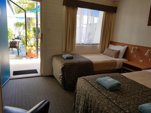 ClermontにあるPeppercorn Motelのベッド2台とバルコニーが備わるホテルルームです。