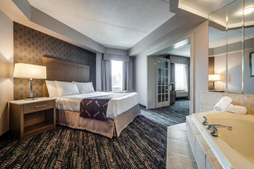 ein Hotelzimmer mit einem Bett und einer Badewanne in der Unterkunft Monte Carlo Inn Brampton in Brampton