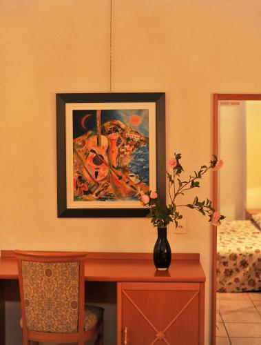 a vase of flowers on a table with a painting at Hotel Ristorante Grotto Serta in Lamone