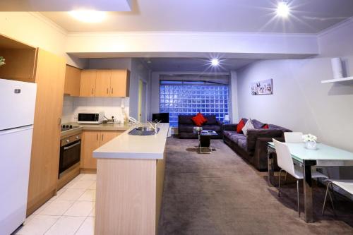 a kitchen and living room with a couch and a table at Flinders Landing Apartments in Melbourne