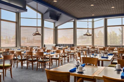 a dining room with tables and chairs and windows at Royal Hotel West Edmonton, Trademark Collection by Wyndham in Edmonton