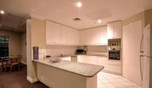 a kitchen with white cabinets and a counter top at Flinders Landing Apartments in Melbourne