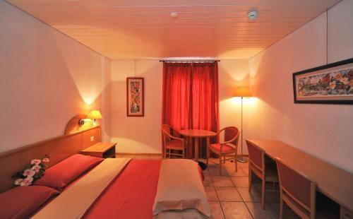a hotel room with a bed and a desk and a table at Hotel Ristorante Grotto Serta in Lamone