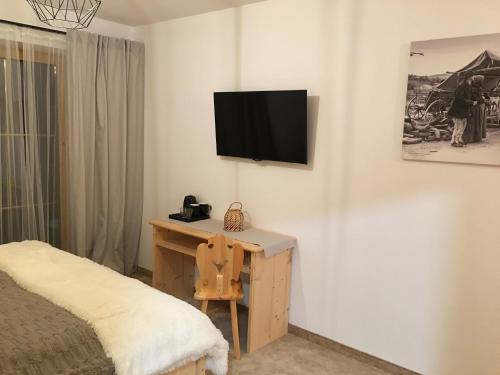 a bedroom with a desk and a television on a wall at Rezydencja Kojsowka in Witów